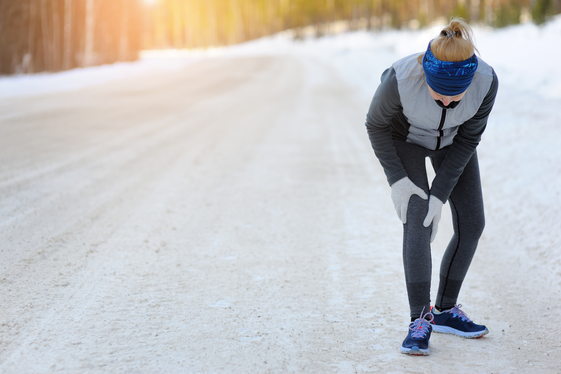 Runner clutching her knee on a snowy road