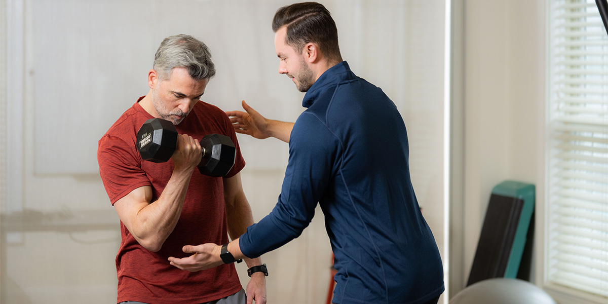 personal trainer with client lifting weights