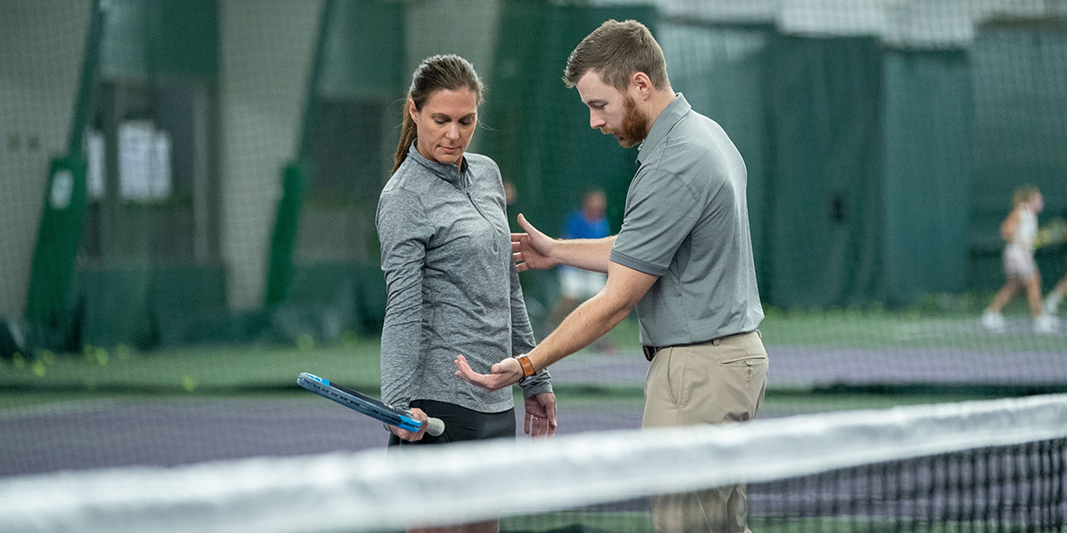 Trainer guiding a tennis player on the court